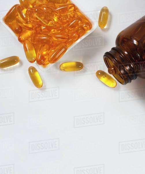 Fish oil capsules in a dish and a bottle Stock Photo Dissolve