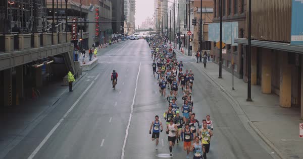 Wide shot of people running on a city street during marathon 4K