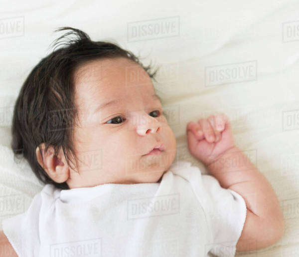 Hispanic infant laying on blanket Stock Photo Dissolve