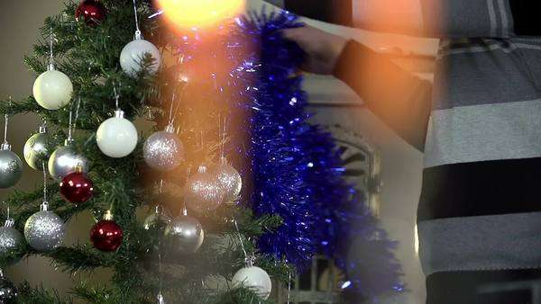 Young Romantic Couple Decorating Christmas Tree By A Fireplace