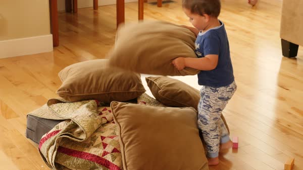 A Toddler Builds A Blanket And Pillow Fort On The Floor Of His