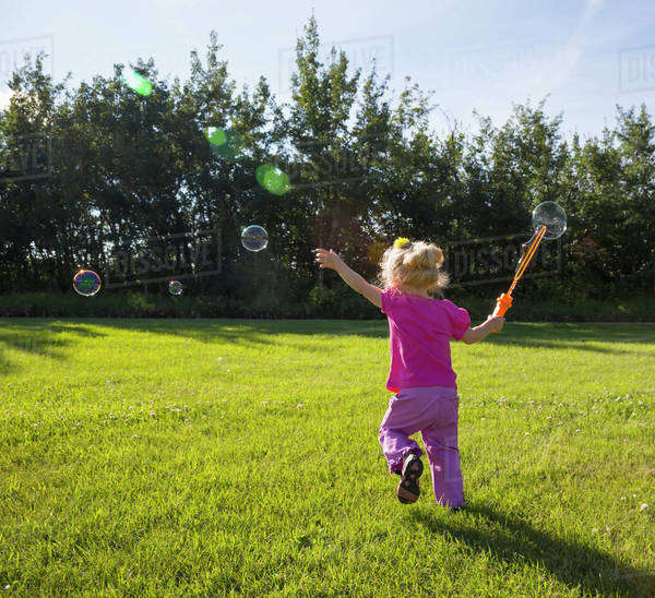 Young girl running in a park making bubbles; St. Albert, Alberta