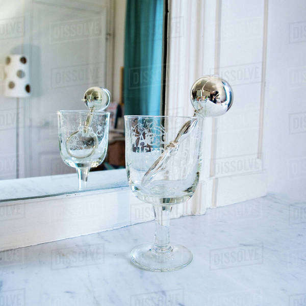 Silver rattle in stemmed glass in front of mirror Stock Photo Dissolve