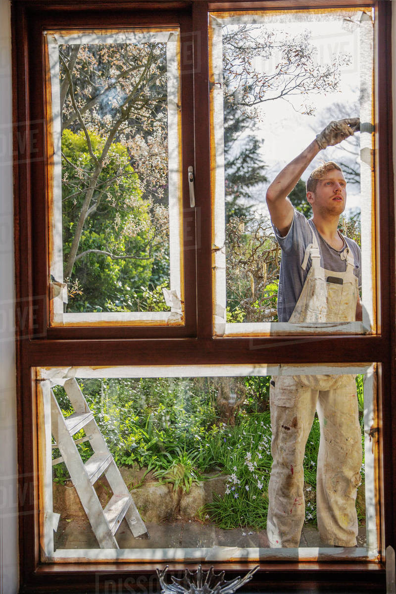 Male painter painting home exterior window trim Stock Photo Dissolve