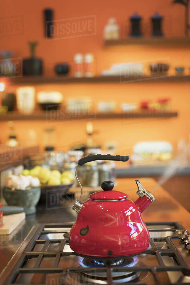 Red tea kettle steaming on stovetop in domestic kitchen Stock Photo Dissolve