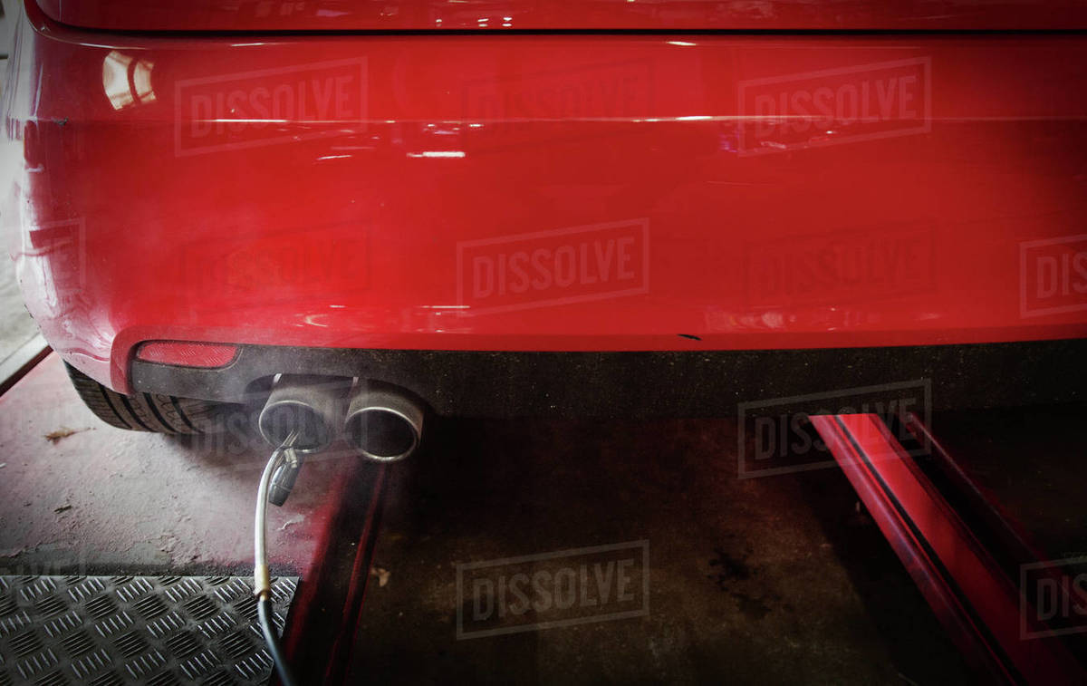 Equipment connected to exhaust pipe on car in auto repair shop Stock