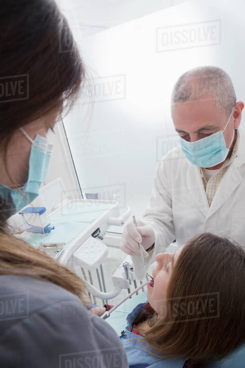 Dentist and hygienist cleaning patient's teeth Stock Photo Dissolve
