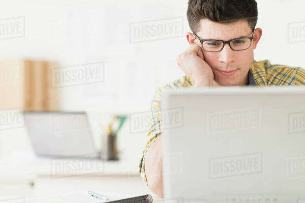 Young man using computer - Stock Photo - Dissolve