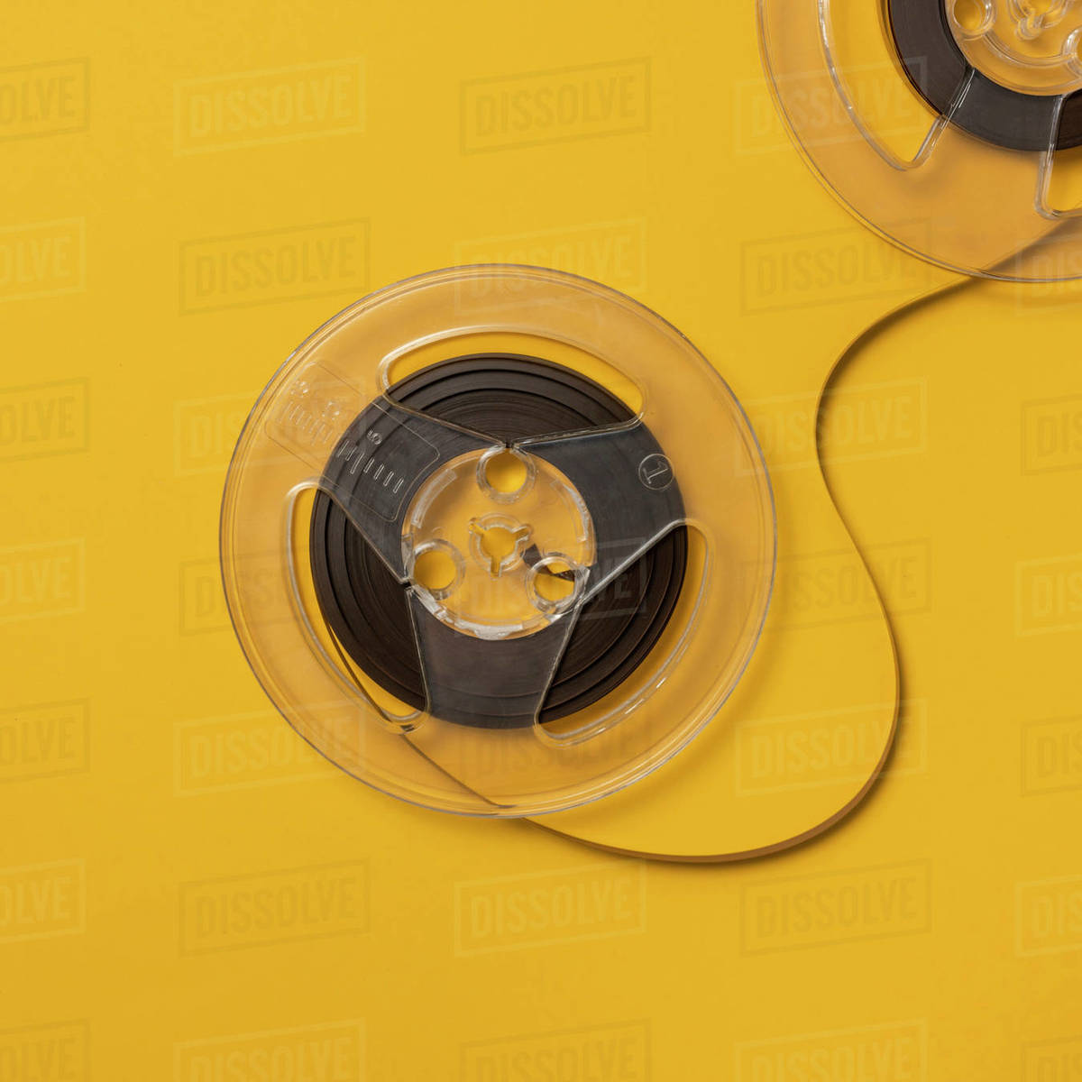 Overhead view of retro recording tape reels against yellow background Stock Photo Dissolve