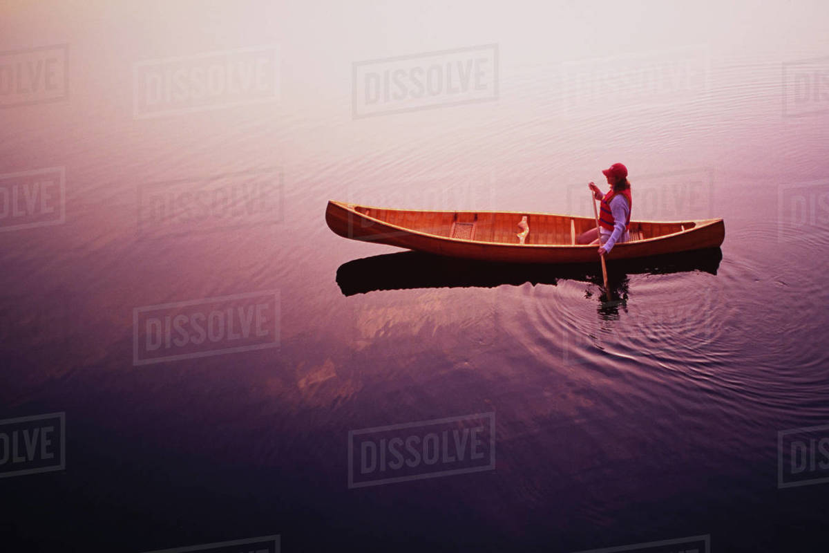 High angle view of woman paddling canoe on Lake Placid at sunrise, Adirondacks State Park