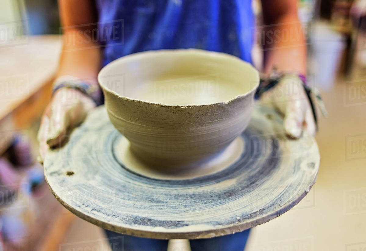 Female potter holding clay bowl Stock Photo Dissolve