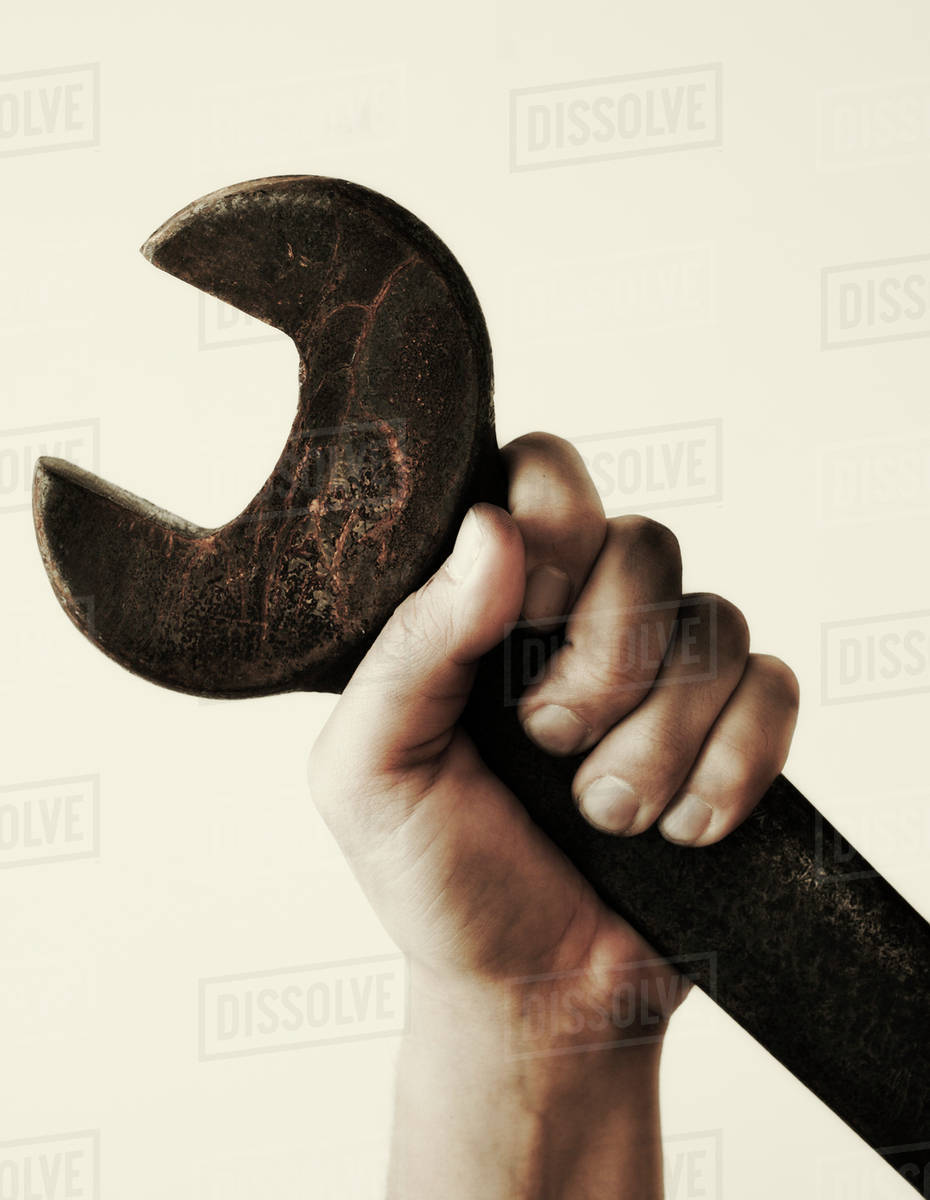 Hand holding wrench, studio shot Stock Photo Dissolve