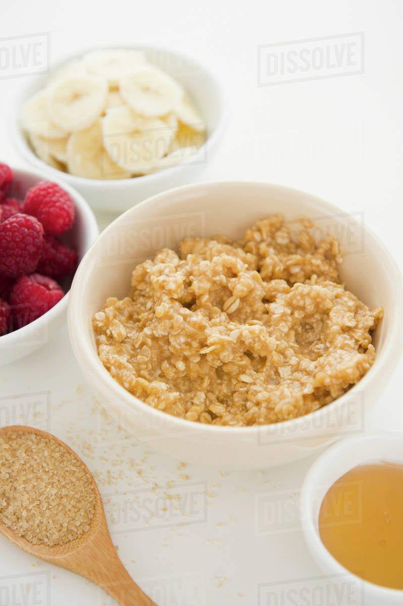 Close up of oats and fruits in bowls, studio shot Stock Photo Dissolve