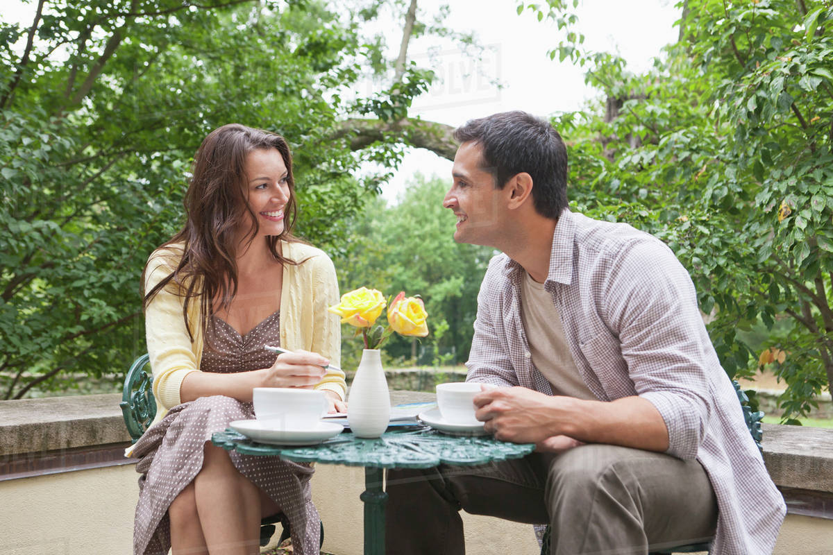 Happy couple sitting at table at outdoor cafe Stock Photo Dissolve