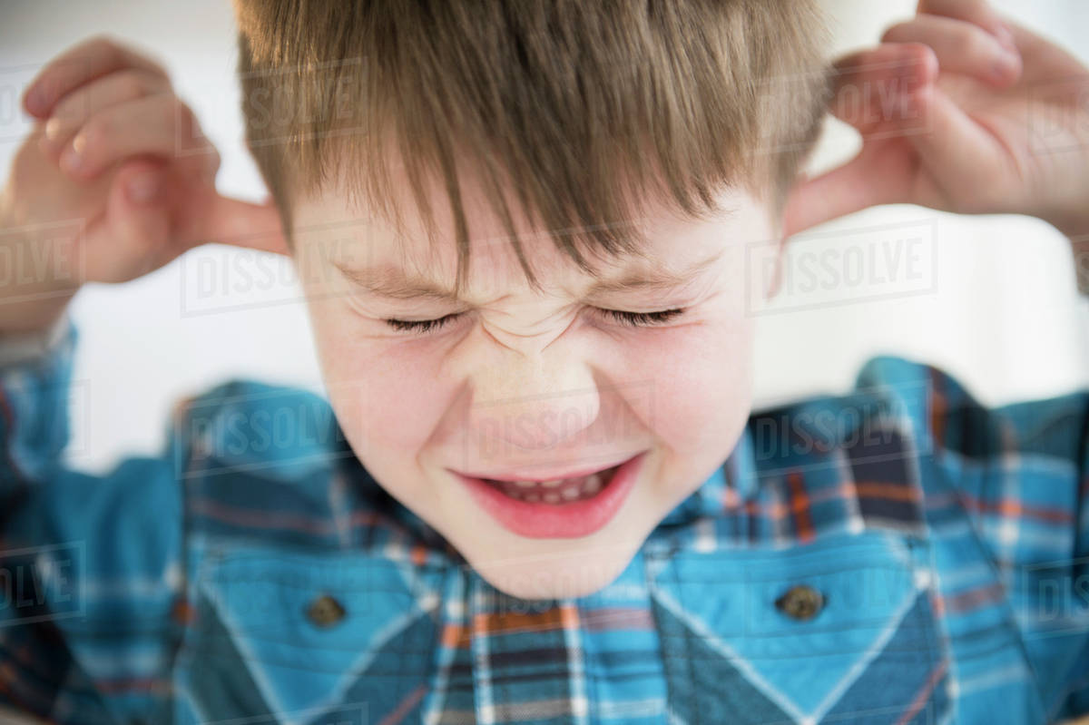 Portrait of boy (45) sticking fingers in his ears Stock Photo Dissolve