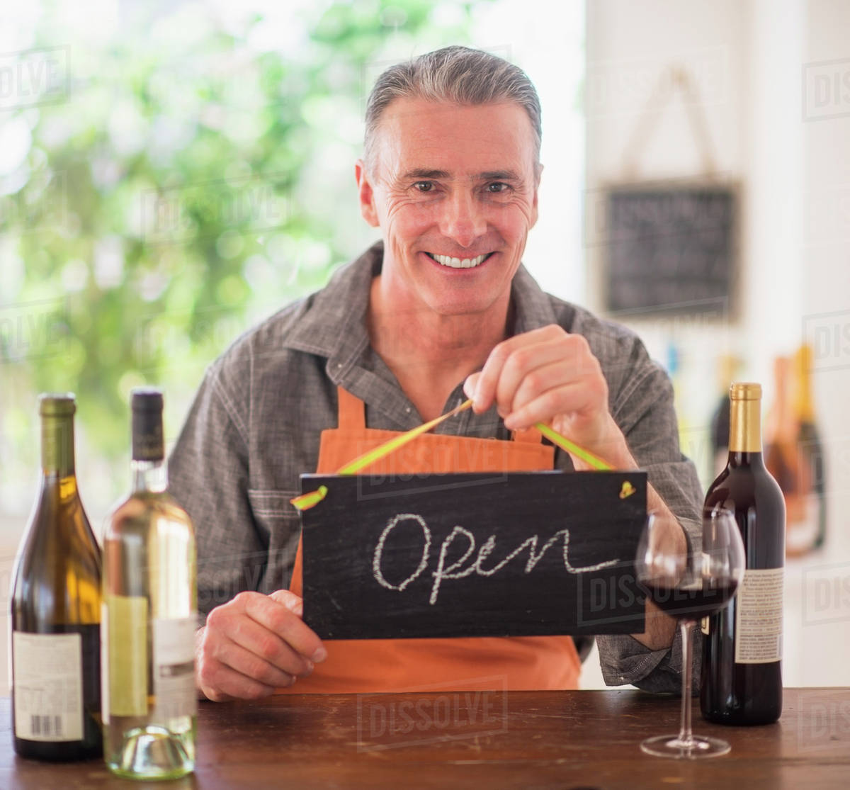 Portrait of wine store owner holding open sign Stock Photo Dissolve
