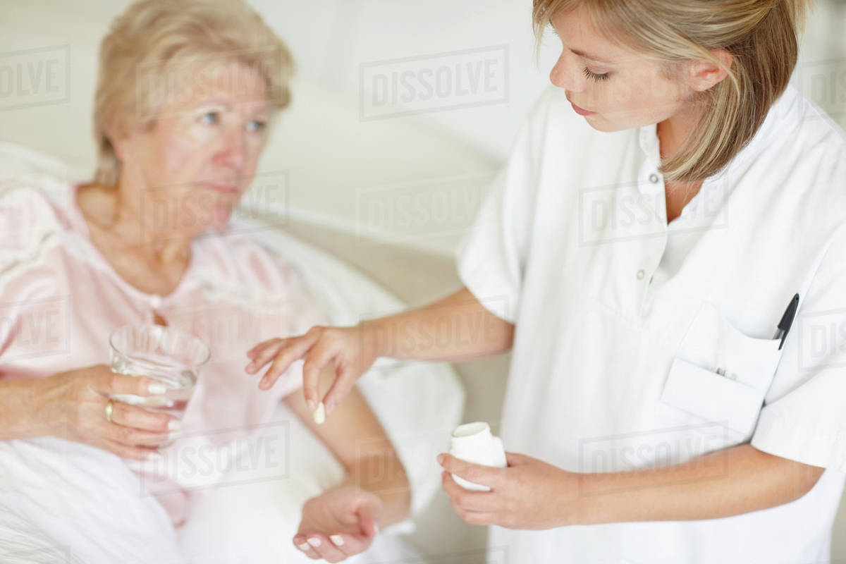 Nurse giving pill to senior woman Stock Photo Dissolve