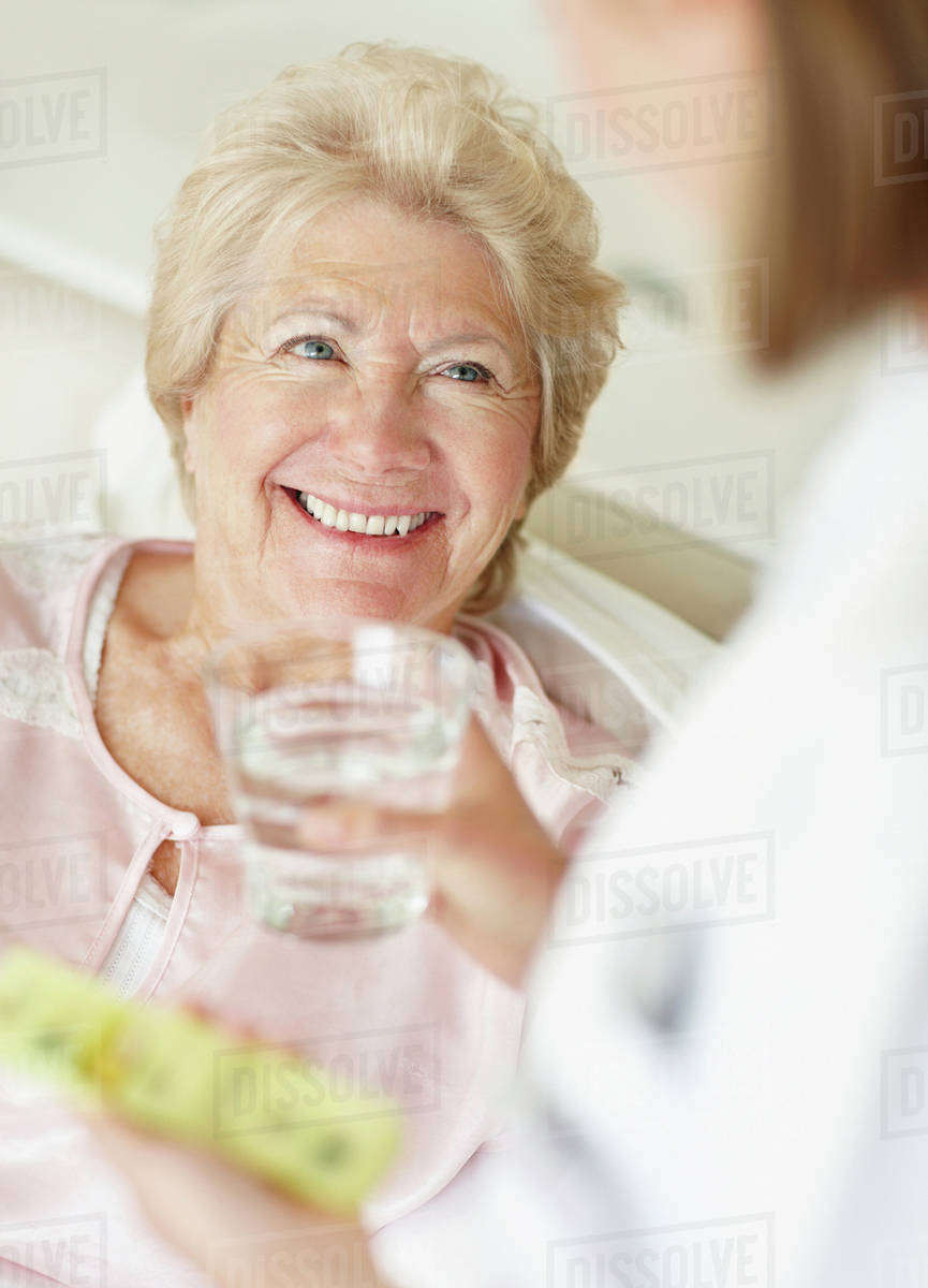 Nurse giving pill to senior woman Stock Photo Dissolve