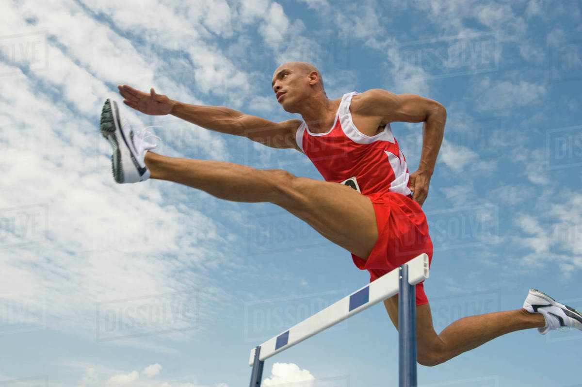 Runner jumping over hurdle Stock Photo Dissolve