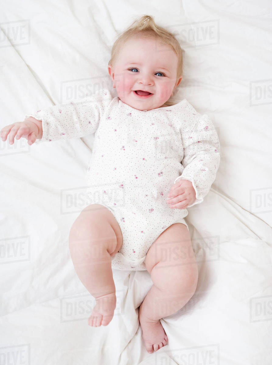 Baby laying on bed Stock Photo Dissolve