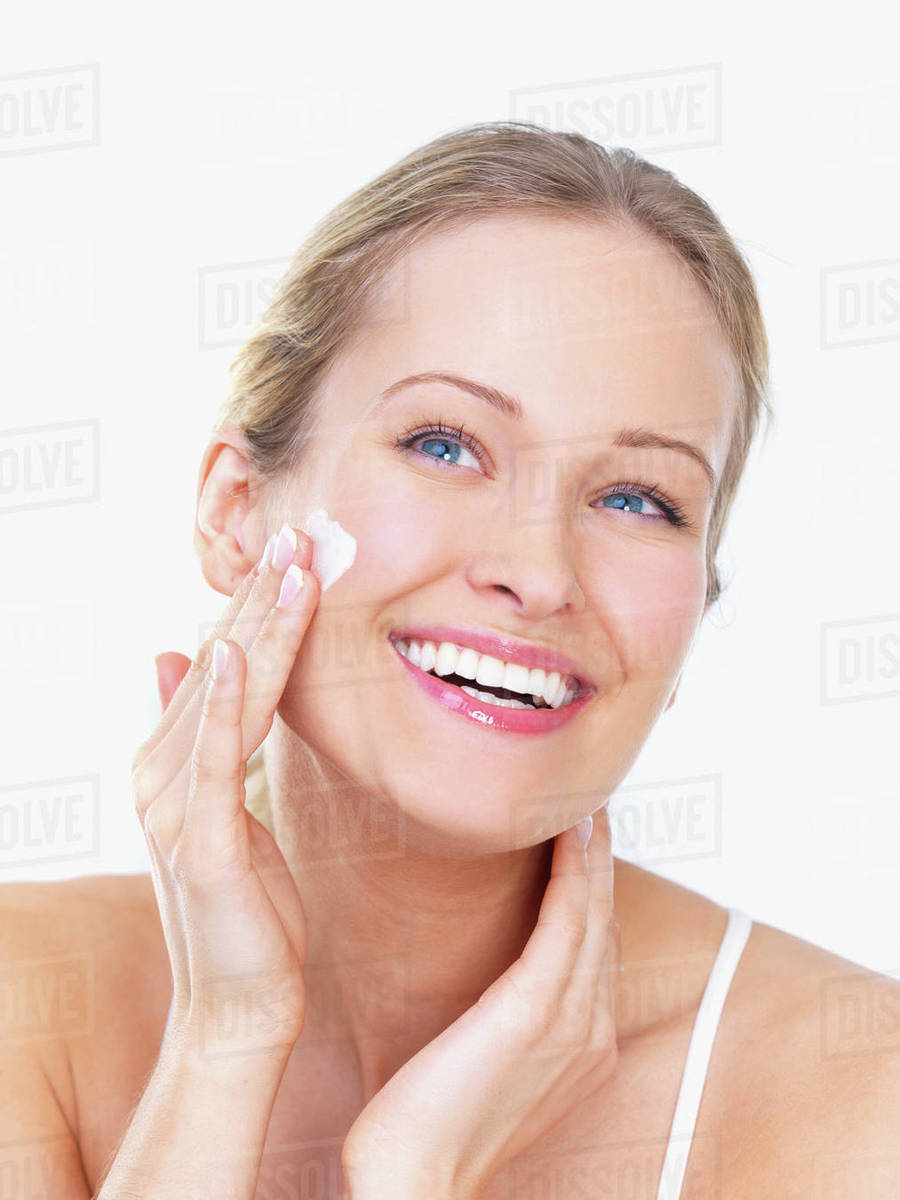 Woman applying face cream Stock Photo Dissolve