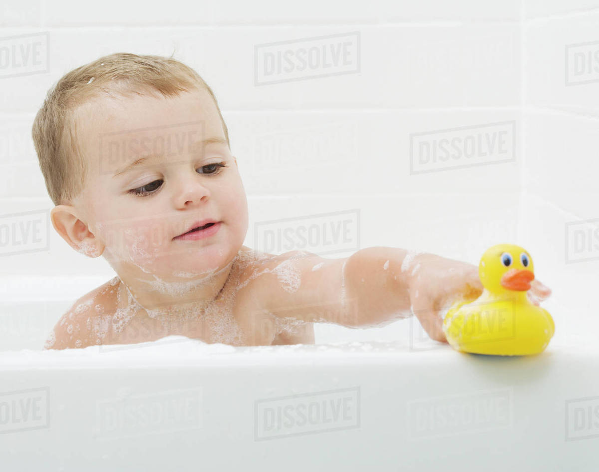 Baby playing with rubber duck in bath Stock Photo Dissolve