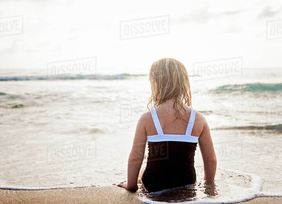 Girl (45) lying down in water on beach Stock Photo Dissolve