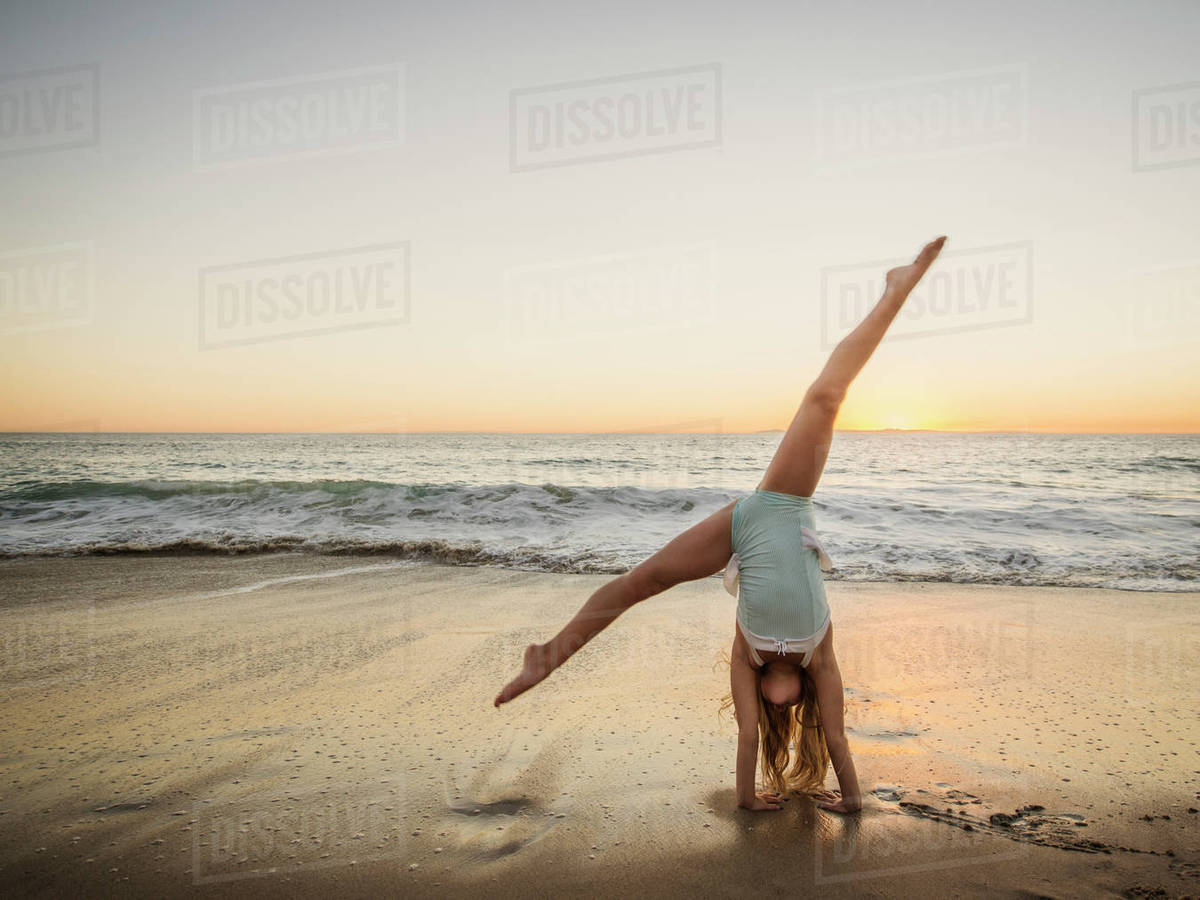 Girl (89) doing cartwheel on beach Stock Photo Dissolve