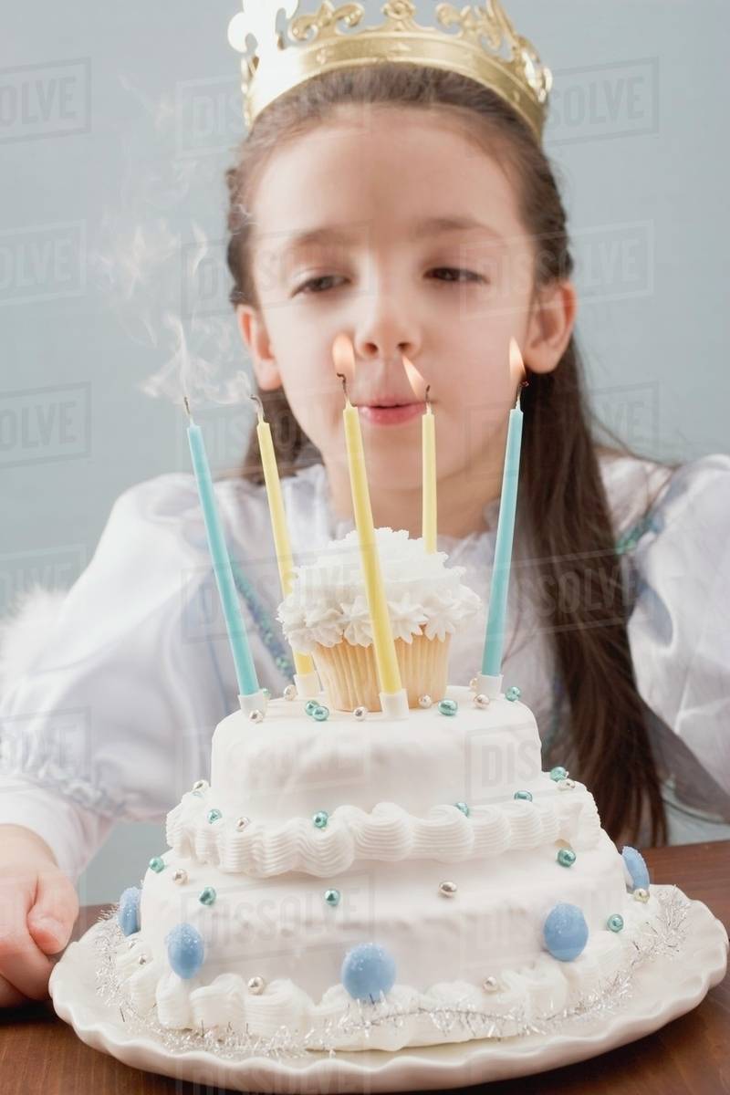 Little princess blowing out candles on birthday cake Stock Photo