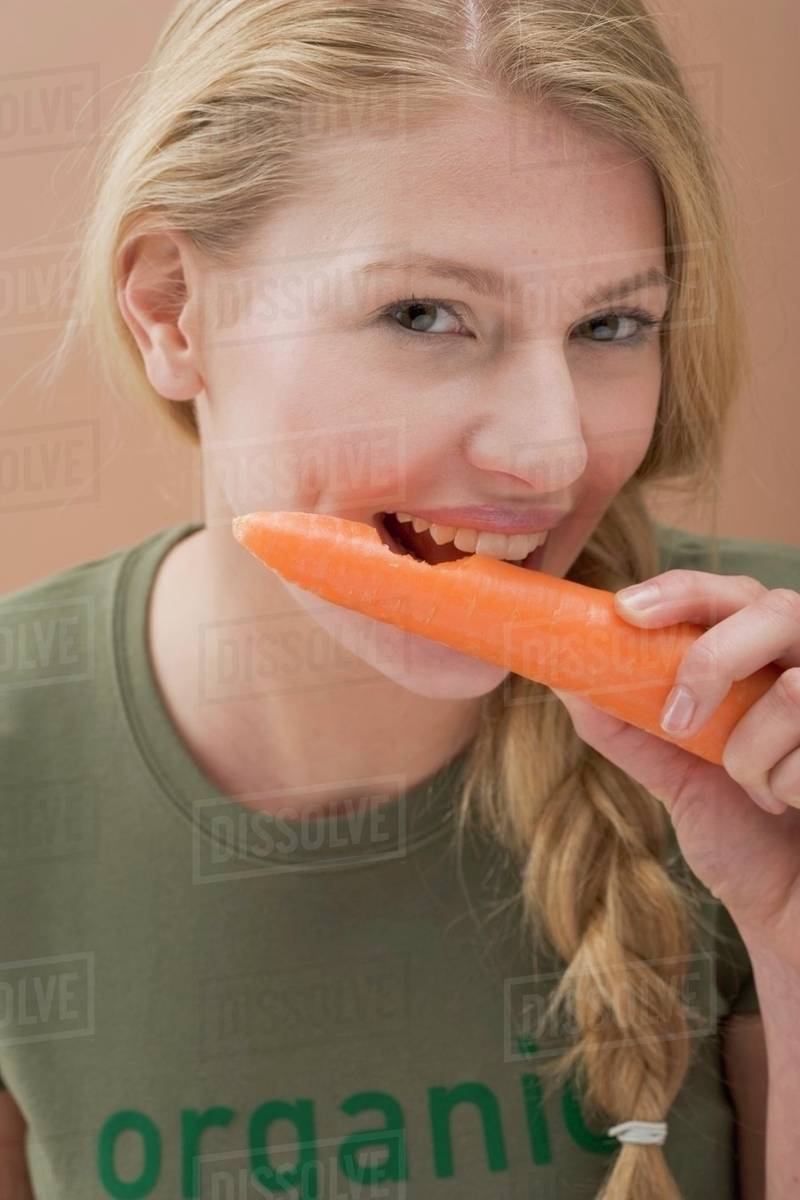 Woman biting a fresh carrot Stock Photo Dissolve