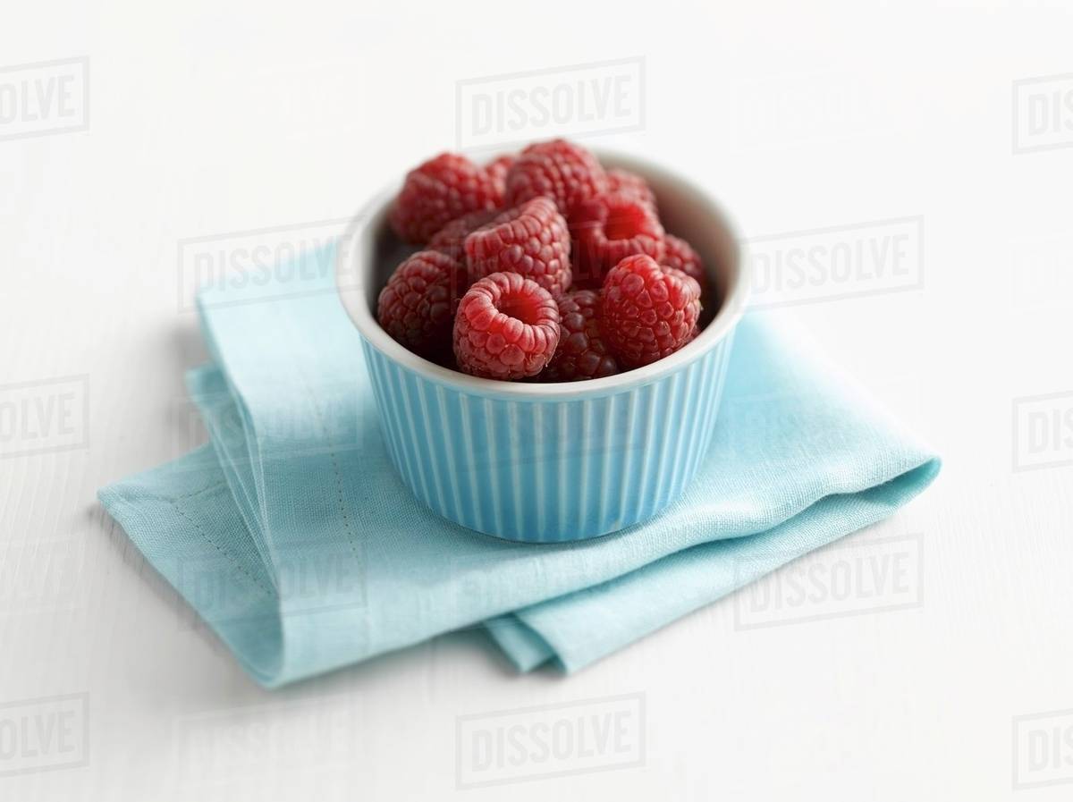 Raspberries in pale blue ramekin Stock Photo Dissolve