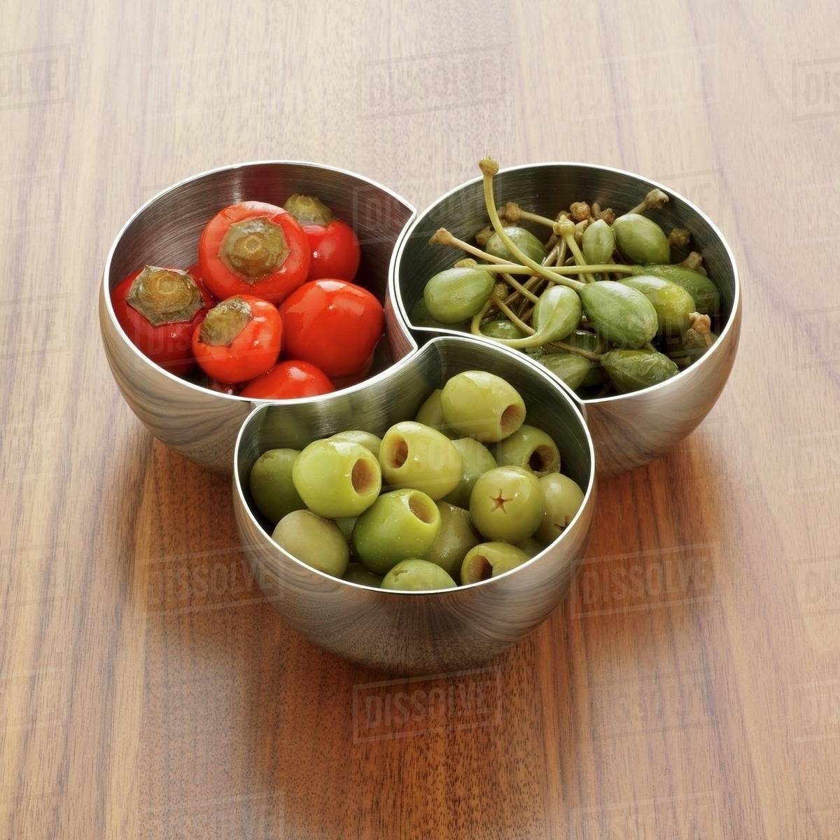 Chillies, giant capers and olives in small bowls Stock Photo Dissolve