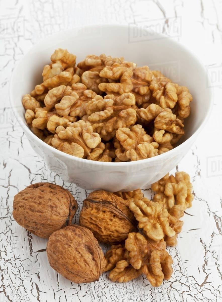 A bowl of walnuts with a whole nuts and 