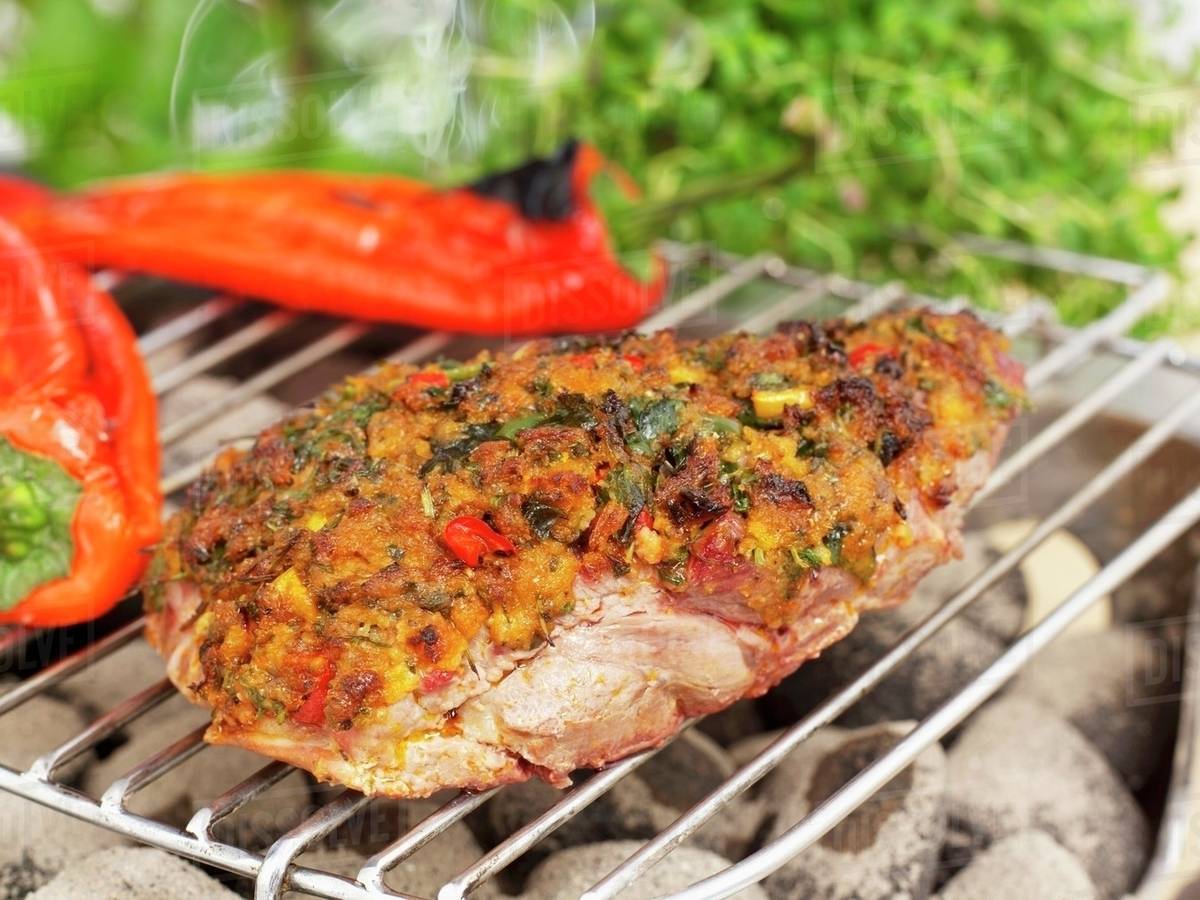 A lamb steak with a herb crust and red peppers on a barbecue Stock
