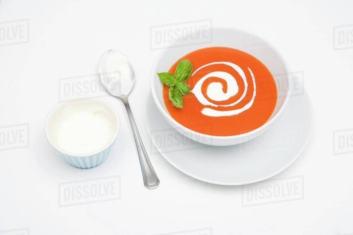Cream of tomato soup with sour cream and basil Stock Photo Dissolve