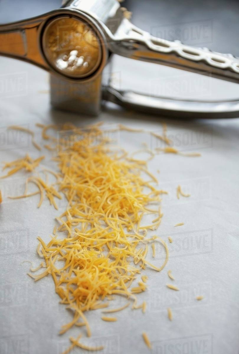 Grated cheddar and a cheese grater Stock Photo Dissolve