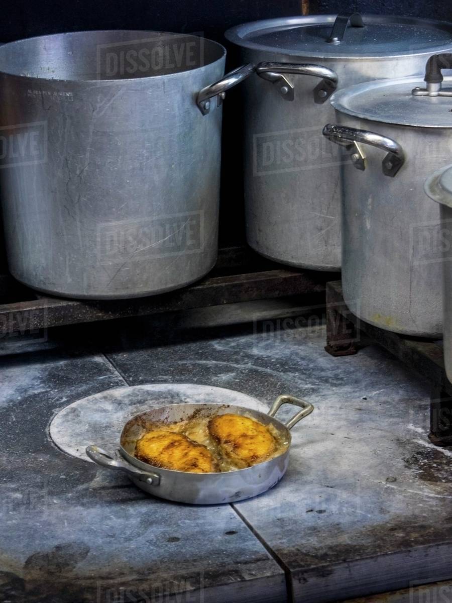Breaded chicken breast fried in butter on the hob in a commercial