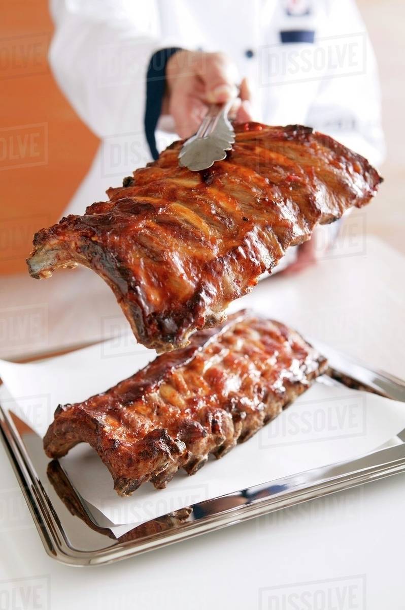 A chef holding grilled spare ribs with tongs - Royalty-free Stock Photo ...
