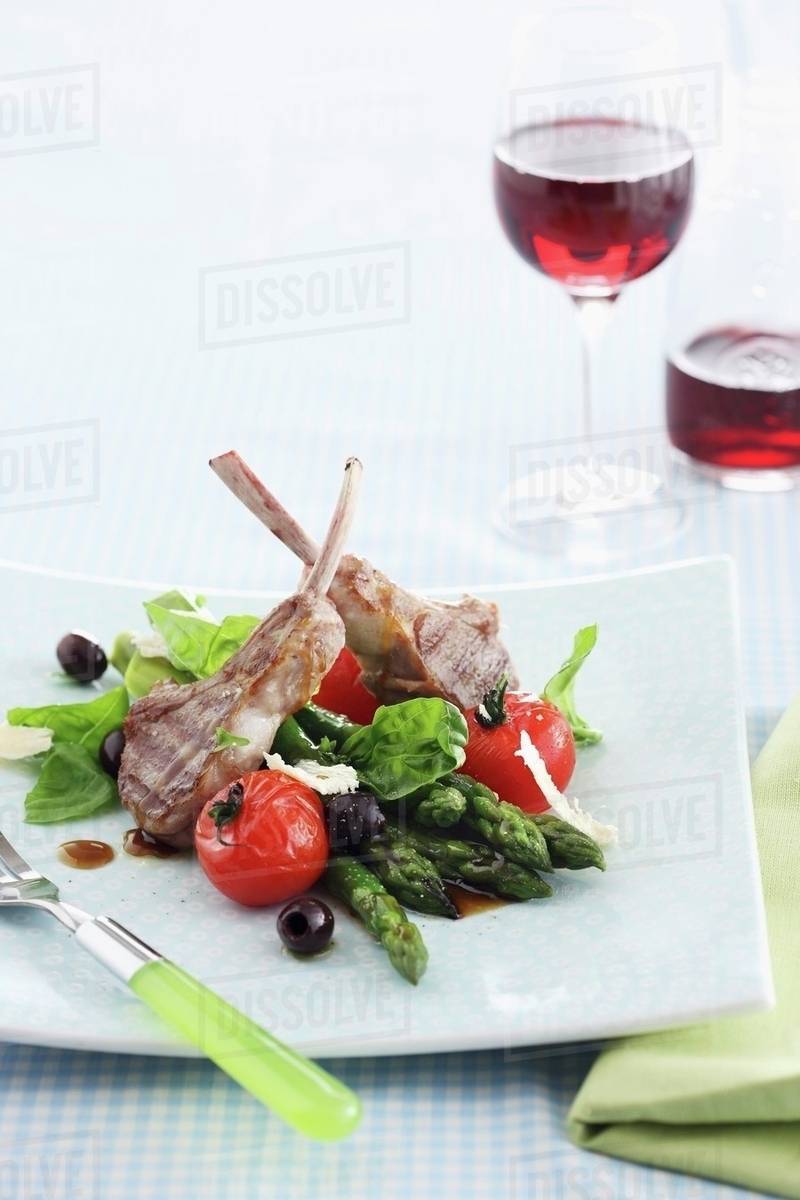Lamb chops with asparagus, olives and tomatoes Stock Photo Dissolve