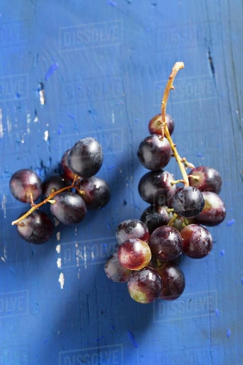 Red grapes on a blue wooden tabletop Stock Photo Dissolve