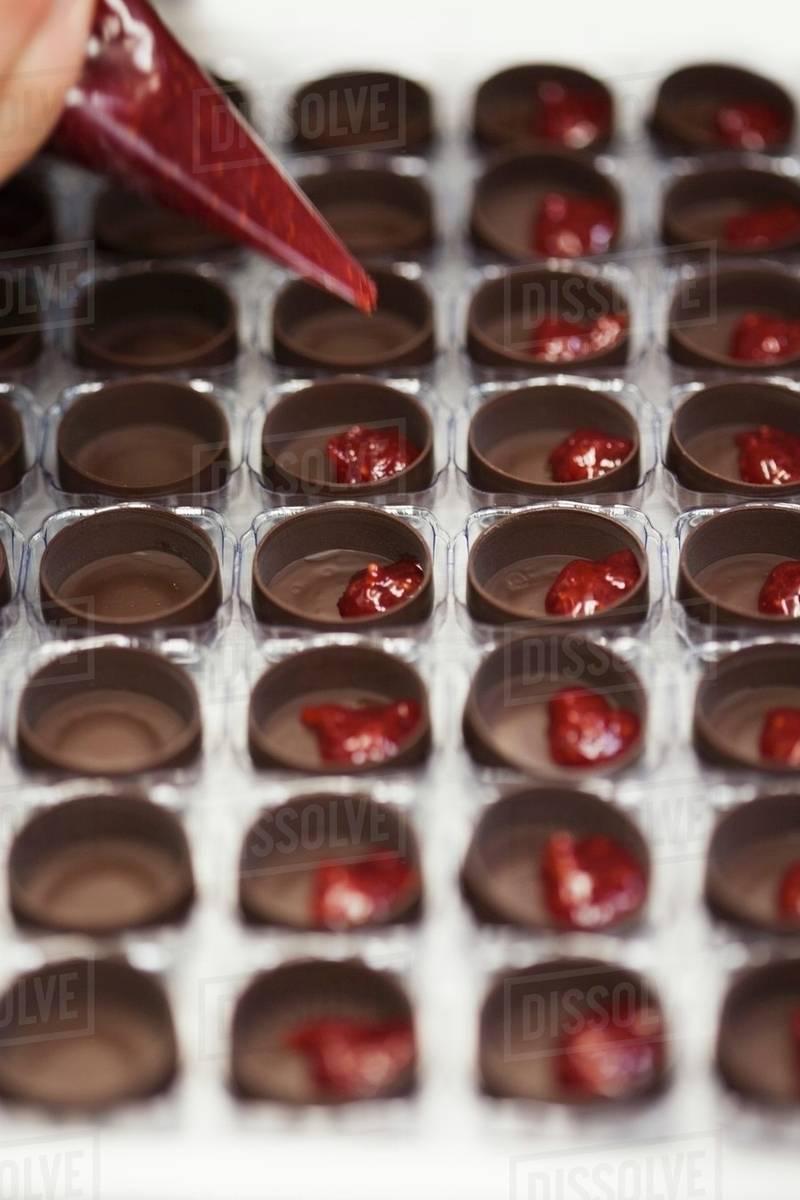 Filling Chocolate Molds with Raspberry Filling Stock Photo Dissolve