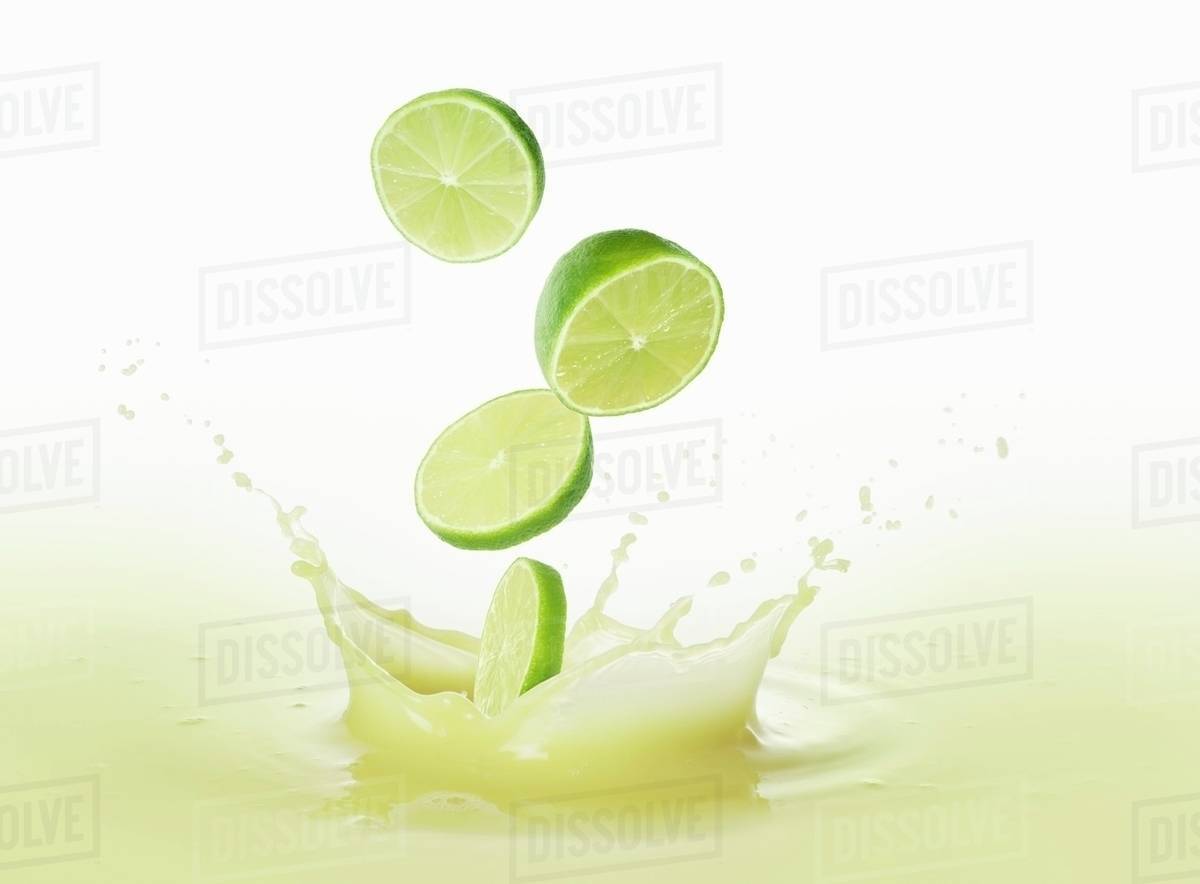 Limes falling into lime juice Stock Photo Dissolve
