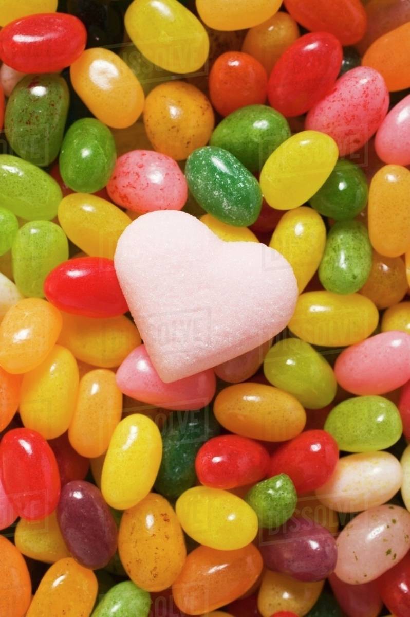 Coloured jelly beans & pale pink sugar heart (fullframe) Stock Photo