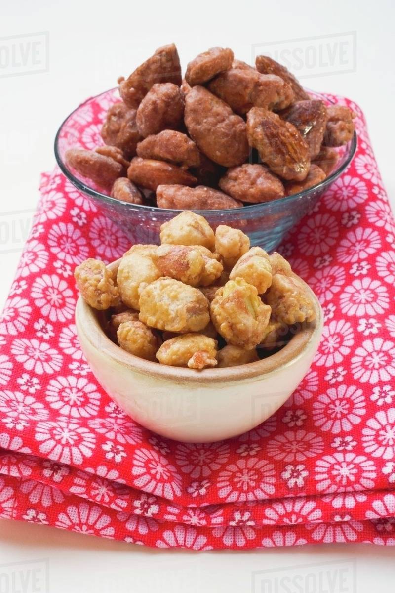 Assorted nuts to nibble in bowls on patterned cloth Stock Photo