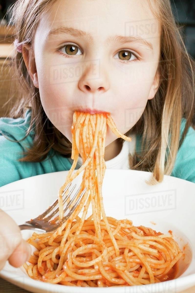 Girl eating spaghetti with tomato sauce Stock Photo Dissolve