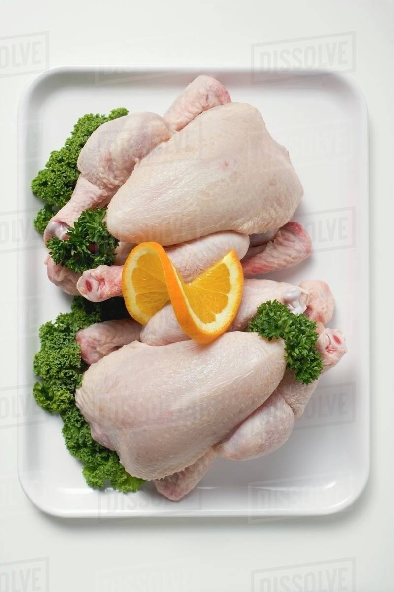 Two fresh chickens garnished with parsley and orange Stock Photo