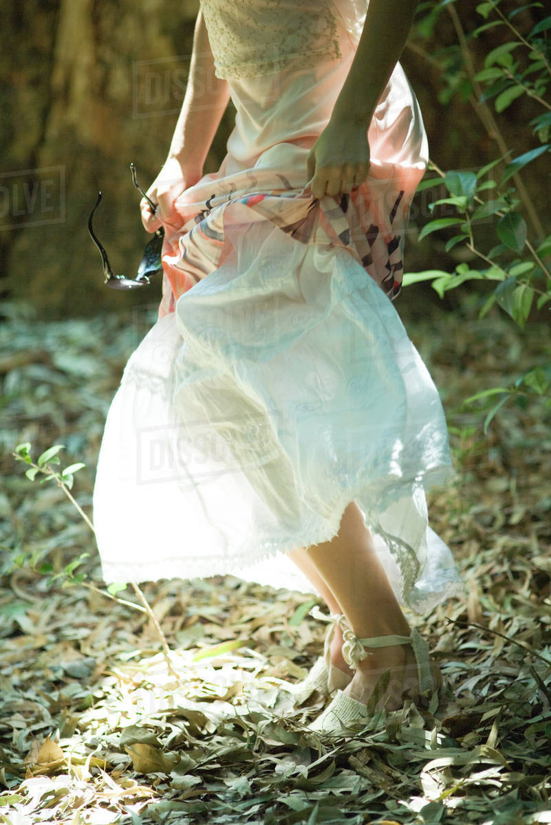 Young woman standing in woods, lifting up skirt, waist down - Royalty-free  Stock Photo | Dissolve