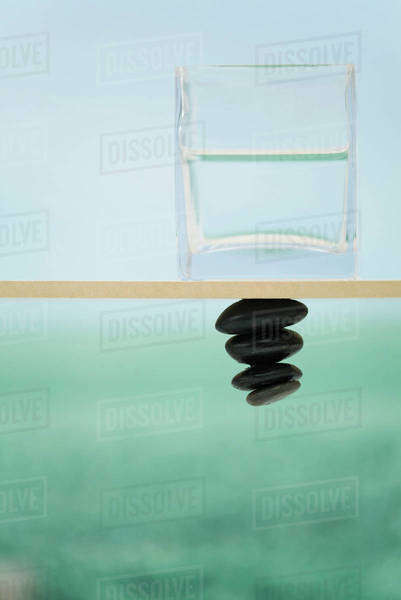 Glass container filled with water sitting on ledge, pile of stones ...