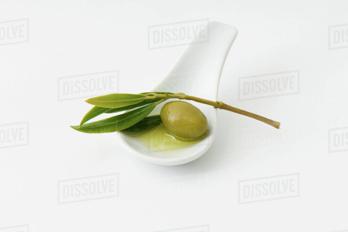 Green olive in spoon, leaf garnish Stock Photo Dissolve
