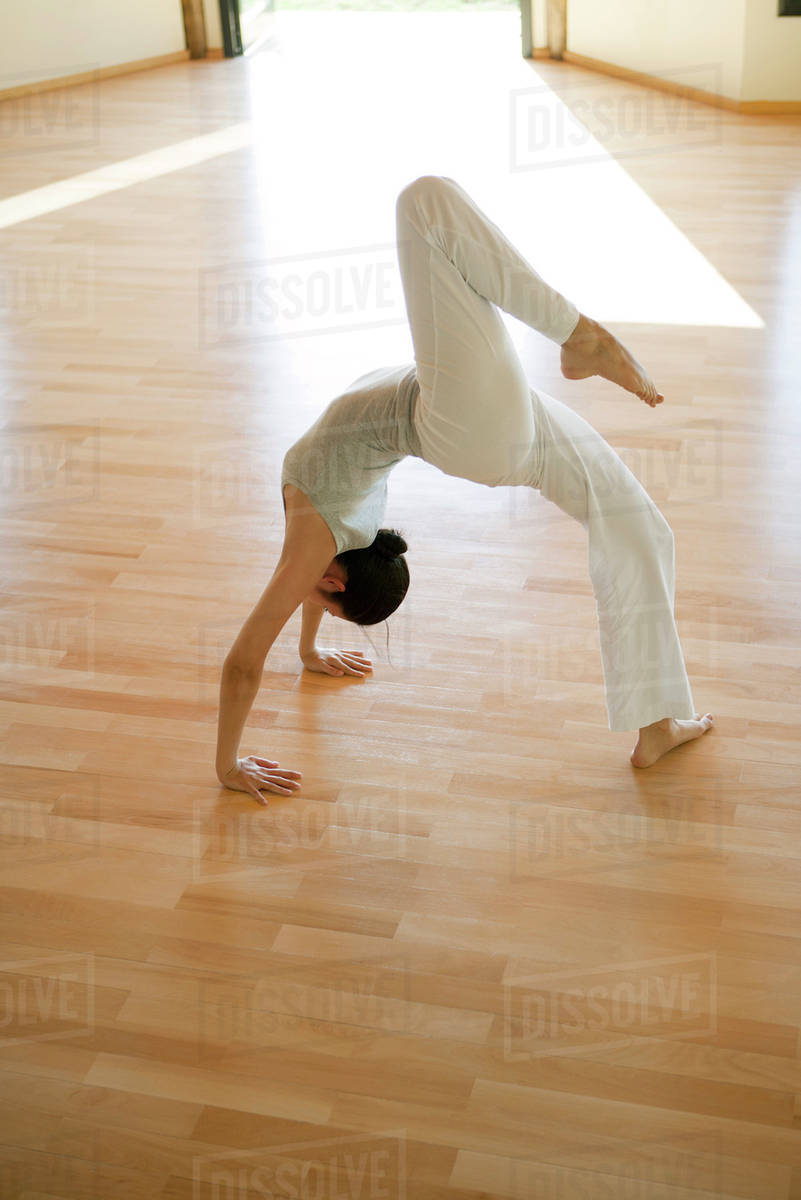 Woman doing one-legged wheel pose - Stock Photo - Dissolve